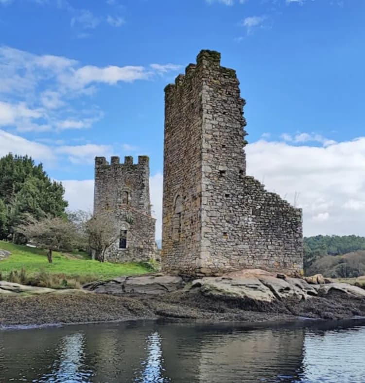 Two ruined stone towers on the rocky bank of the Ulla.