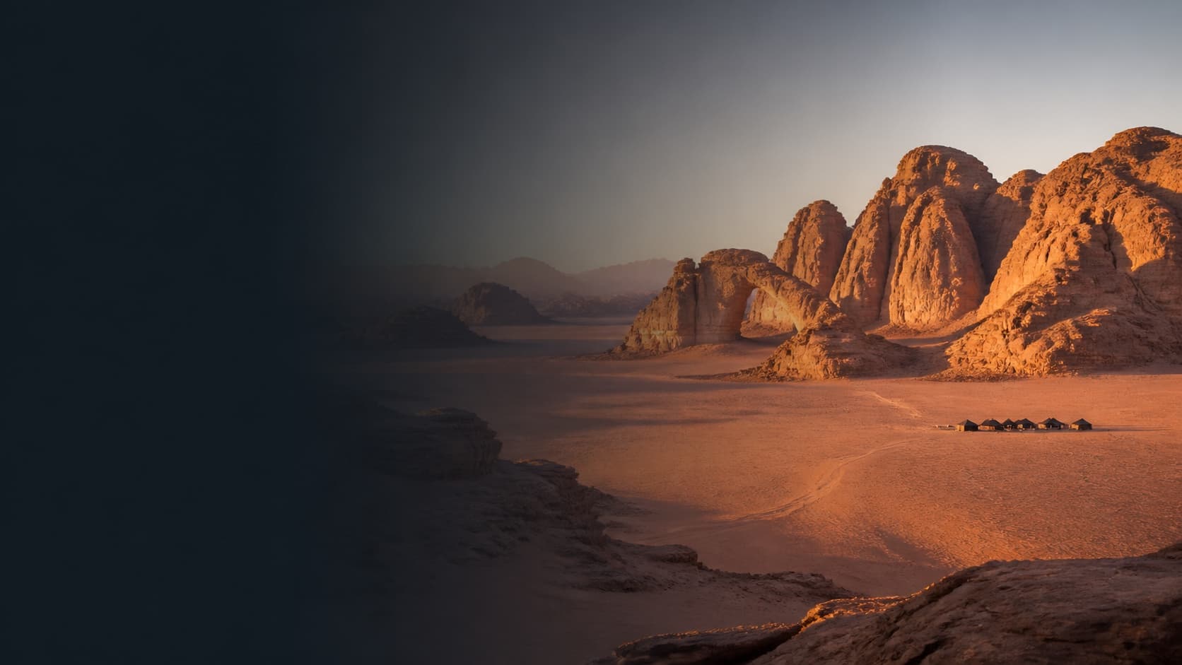 The sandstone formations and open desert of Wadi Rum at dawn.